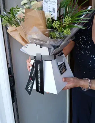 Soft flowers in a white Welch ribbon carrier