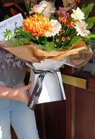 Warm orange and peach flowers in a Welch carrier
