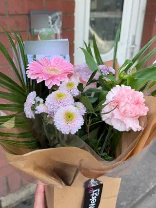 Pink gerberas and carnations in kraft wrapping