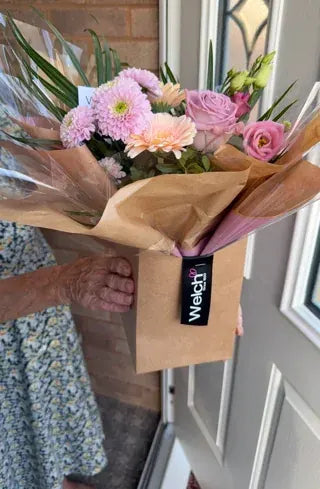 Pink and peach flowers in a kraft Welch carrier