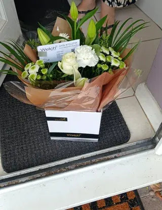 White flowers in a Welch gift box at a doorway