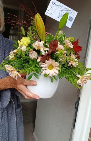 Autumn foliage and pale flowers in a white jug
