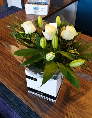 White roses and lily buds in a Welch gift box on a reception desk