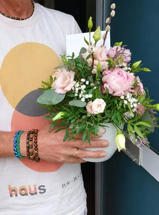 Pink roses and peonies in a white jug held at the doorstep