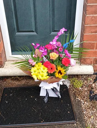 Colourful Welch bouquet with orchids and a sunflower on a doorstep