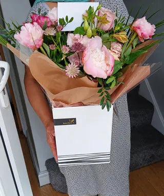 Pink peony bouquet with foliage in a white gift box