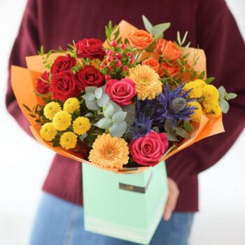 Colourful flower bouquet with pink, red and orange roses, chrysanthemums and thistles in a gift box. The Striking Sunset, an Autumn Bouquet from Welch the Florist | Next Day Flower Delivery UK Florist.
