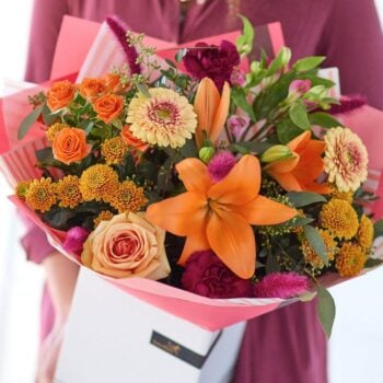 Colorful mixed flower bouquet with roses, lilies, and chrysanthemums in pink wrapping. The Bonfire Beauty, an Autumn Bouquet from Welch the Florist | Next Day Flower Delivery UK Florist.