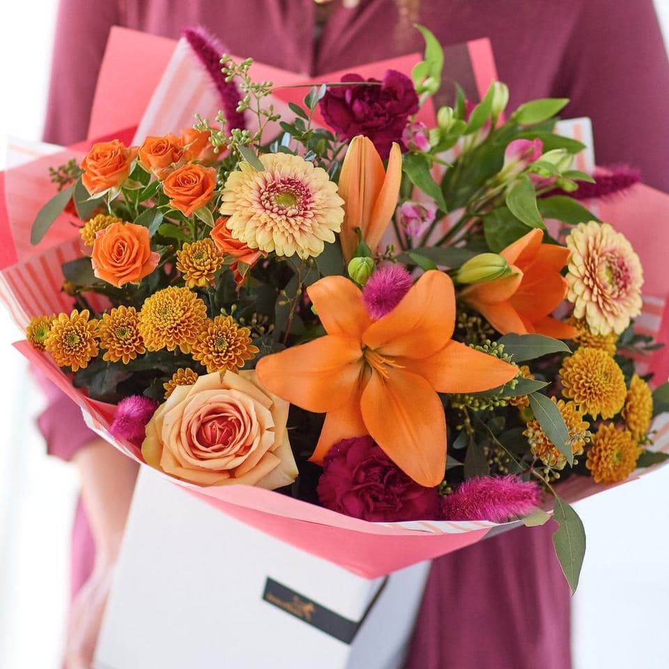 Colorful mixed flower bouquet with roses, lilies, and chrysanthemums in pink wrapping. The Bonfire Beauty, an Autumn Bouquet from Welch the Florist | Next Day Flower Delivery UK Florist.