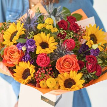 Bright sunflower, red roses, and purple flowers in a colourful bouquet for celebrations. The Sunflower Carnival, an Autumn Bouquet from Welch the Florist | Next Day Flower Delivery UK Florist.